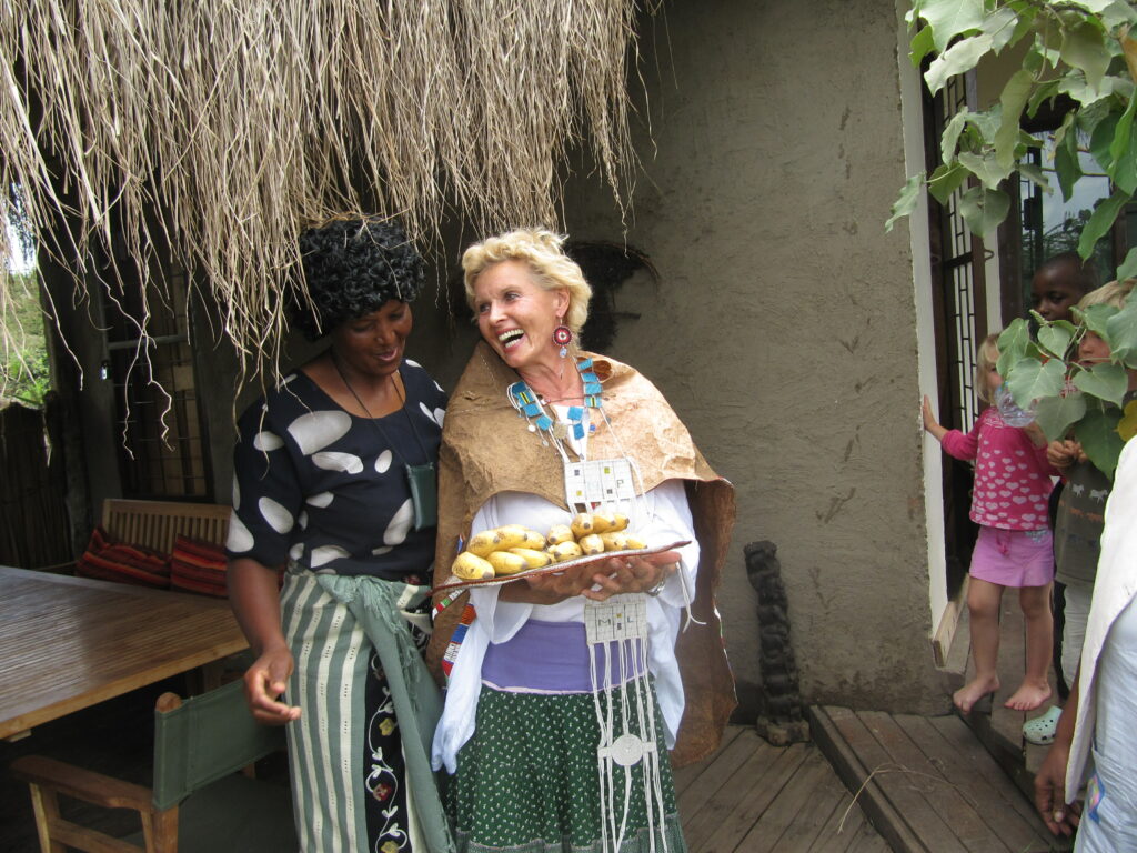 Christine Wallner und eine weitere Dame stehen vor einem Haus mit Strohdach. Das war Frau Wallners erstes Haus in Momella.