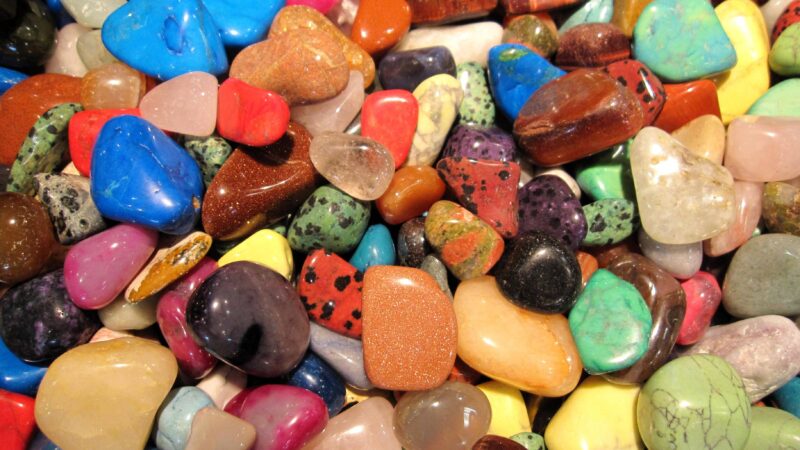 Viele Halb-Edelsteine mit unterschiedlichen Farben, Größen und Formen liegen auf einem Haufen.