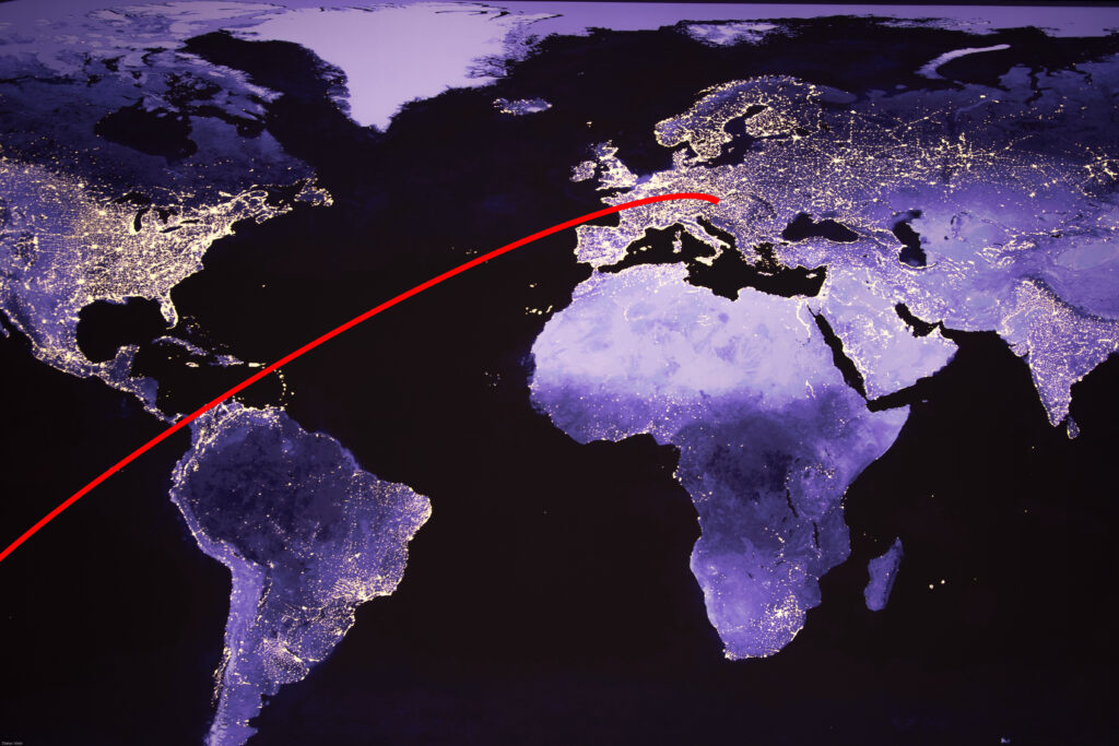 Satellitenaufnahme der Erdoberfläche. Eine rote Linie zeigt symbolisch den Weg einer energetischen Fernanwendung.