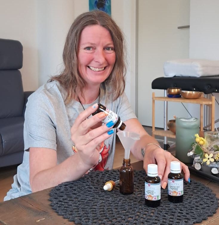 Manuela Mair stellt eine Bachblütenmischung her. Sie gibt dabei aus einem Fläschchen in ihrer Hand Tropfen in ein anderes Fläschchen, das vor ihr auf einem Tisch steht.