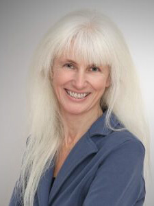 Porträtfoto der Lebens- und Sozialberaterin Sabince Kouicem. Sie hat lange, glatte, weißblonde Haare und trägt einen dunkelblauen Blazer und lächelt in die Kamera.