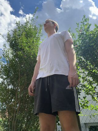 Zwischen einer Wiese und einem Weizenfeld ist die T-Kreuzung einer asphaltierten Straße.