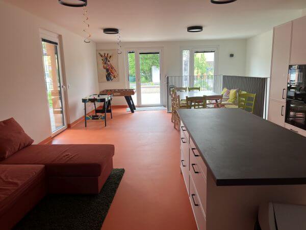 Blick in einen großen Raum mit Tisch und einem Sofa.